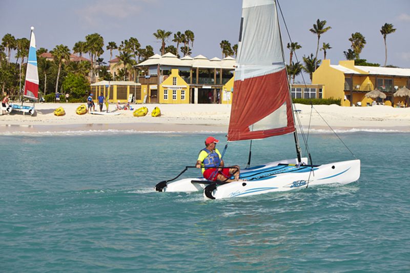 A visitor takes a small catamaran out for a spin in front of Tamarijn Aruba, a laid-back, all-inclusive resort.