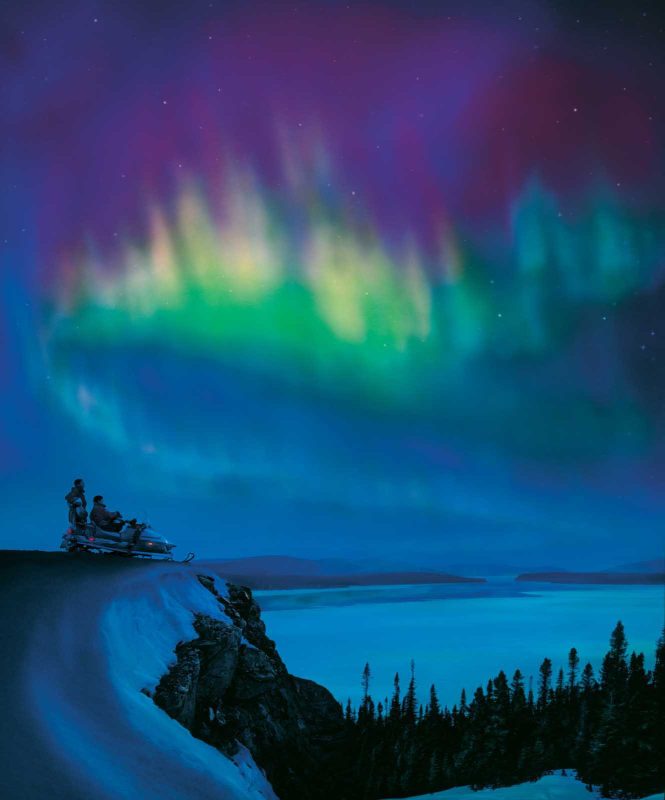 Outdoors lovers pause in their snowmobile to watch the Northern Lights in Labrador.