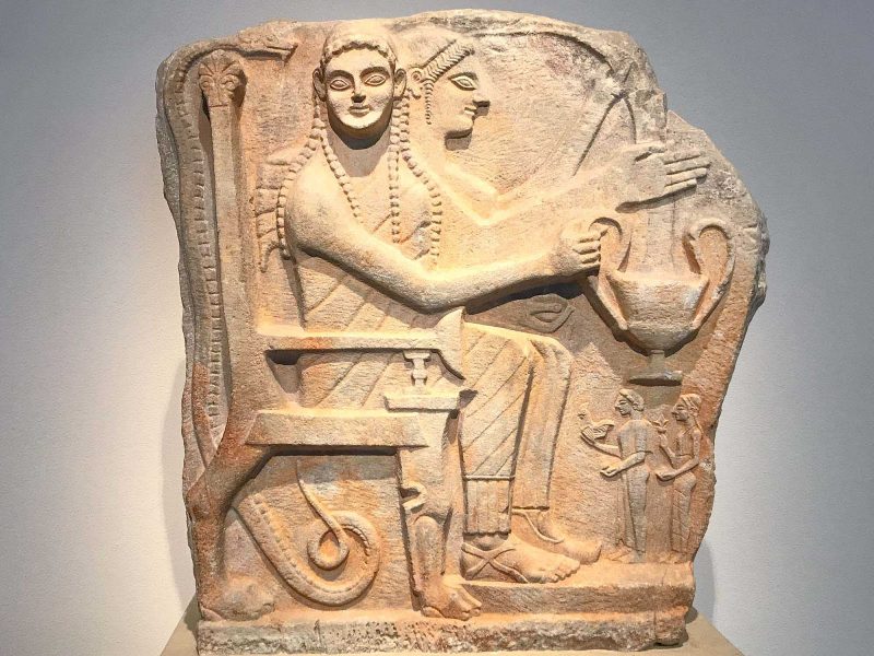 Relief with heroes and worshippers in the Altes Museum of Berlin. It depicts deceased heroes surrounded by a throne, snake and receptacle for offerings.