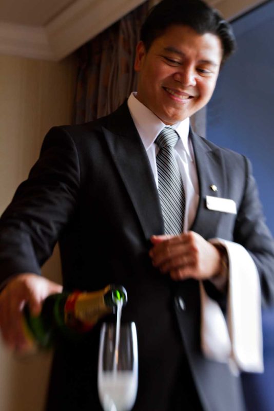 A butler serves Champagne during an Azamara cruise.