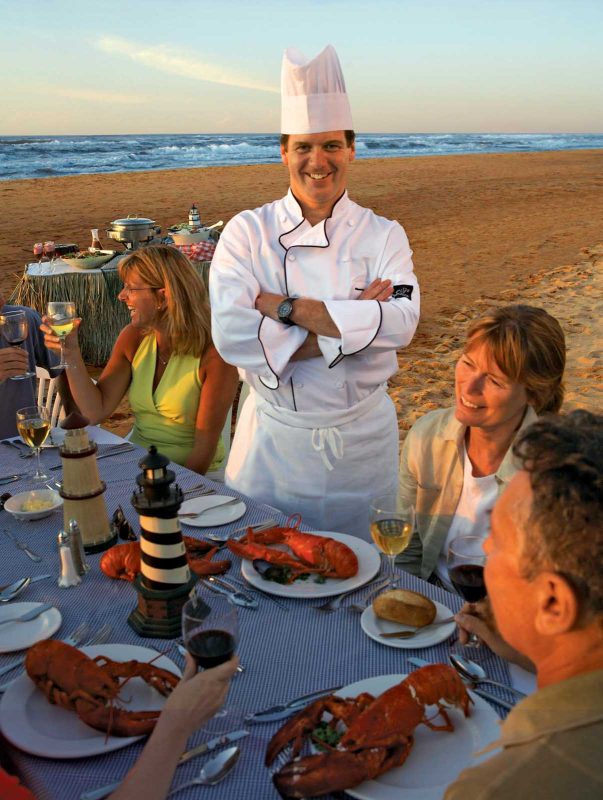 A chef and guests at a lobster dinner on the beach on Prince Edward Island, Canada.