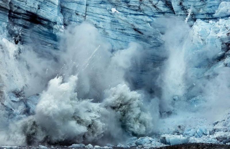 A tidewater glacier breaks off, or calves, on Margerie glacier in Glacier Bay, giving birth to several icebergs.