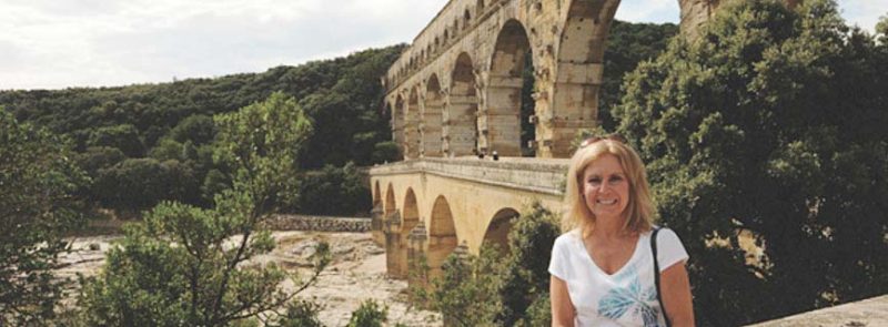 A visitor poses in the front of the ancient Roman aqueduct bridge, Pont du Gard, crossing the Gardon River in southern France.