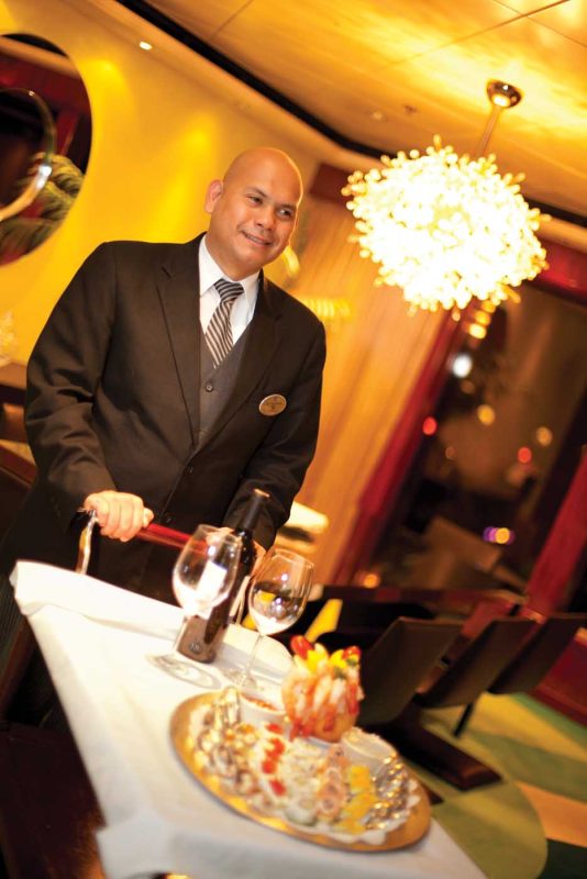 A butler with a tray of canapes and Champagne in The Haven on Norwegian Cruise Line.
