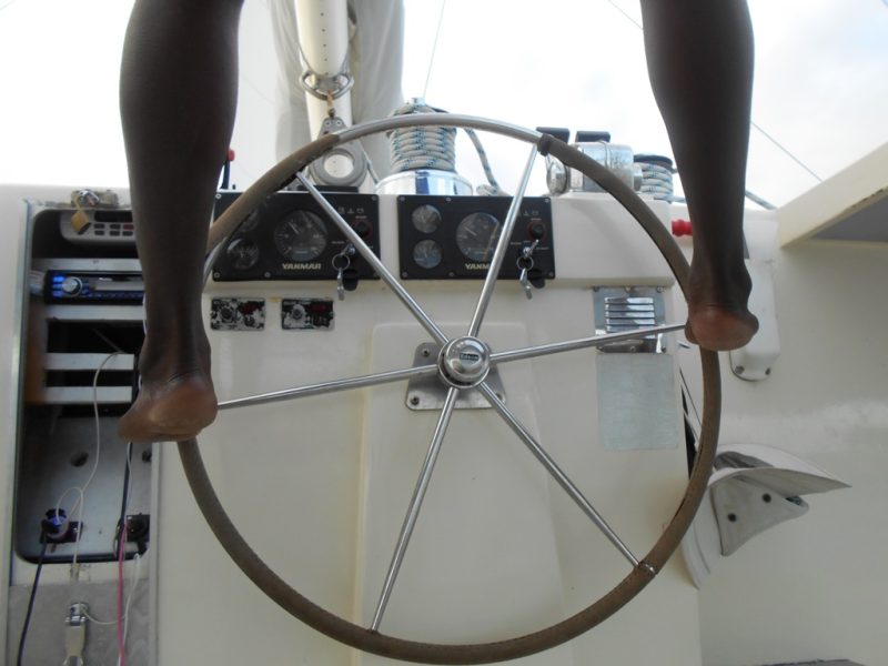 The captain of our St. Kitts catamaran shore excursion steering with his feet