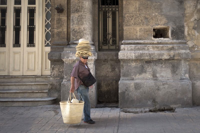 A vendor walks down a street in Havana.