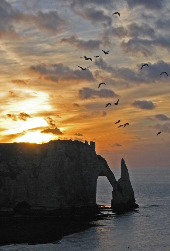 The arch rock and chalk cliffs of d'Etretat are part of the stunning views of Normandy, France.