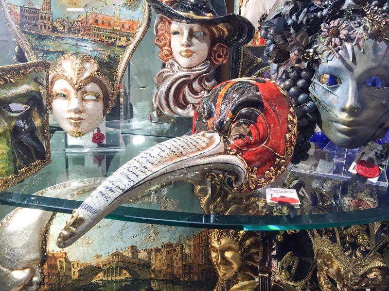 A beaked figurine appears to have a written backstory on its beak in a shop in Venice.
