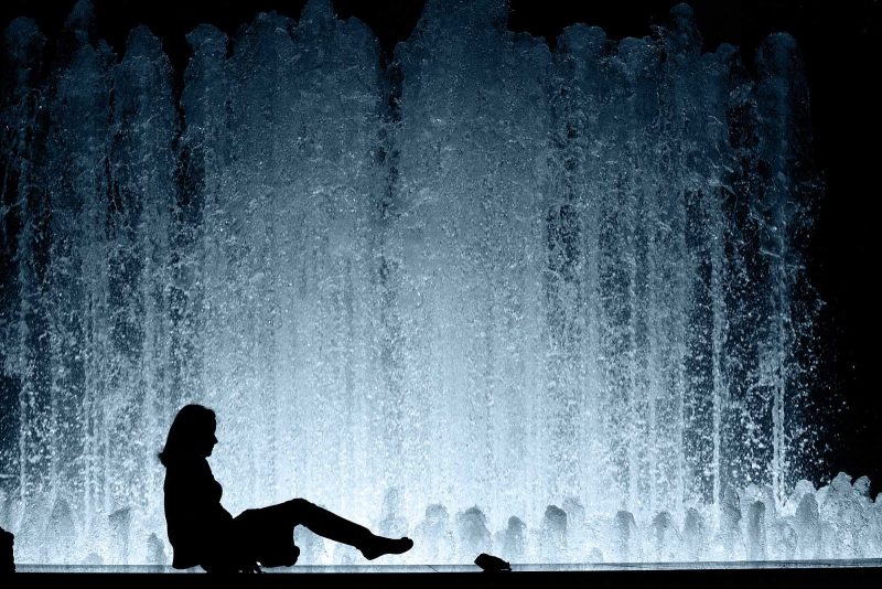 Silhouette of a woman cooling off on a warm spring night in front of the fountain at Lincoln Center.