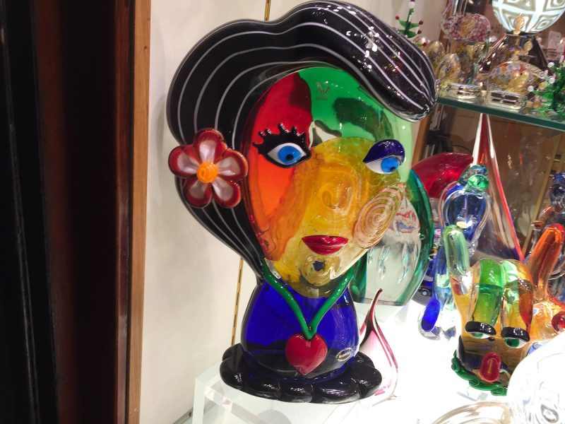 A pouty glass figurine, likely made in Murano, in a tourist shop in Venice.