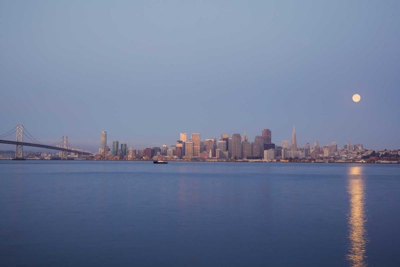 The moon shines down on the San Francisco skyline in the early morming as seen from Treasure Island.