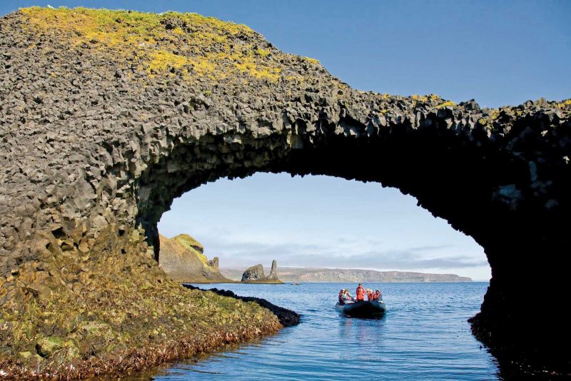 Take a Zodiac boat cruise under a natural arch of basalt on a Lindblad Expeditions adventure.
