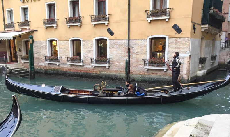 A gondolier prepares to take two travelers out to see Venice's Grand Canal.