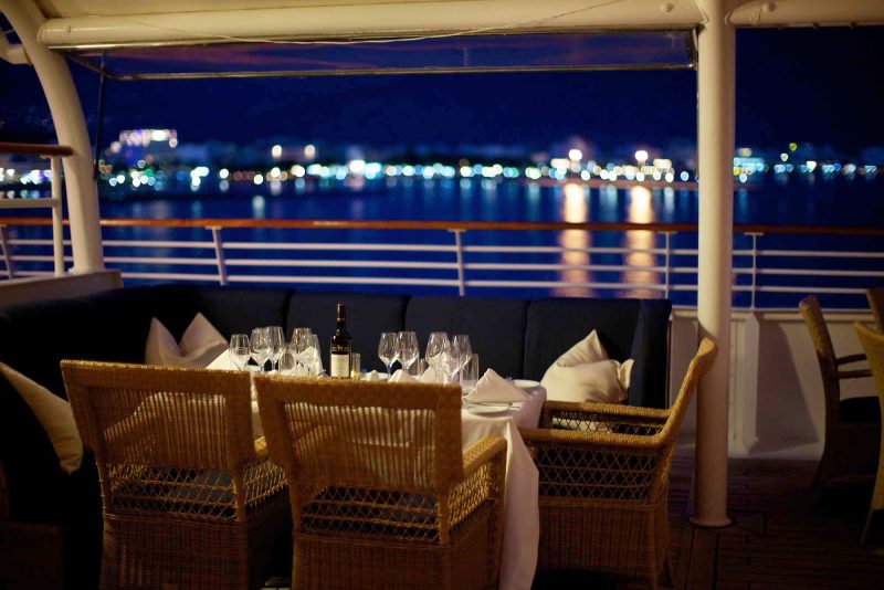 Dine on deck as lights sparkle along the shoreline on a SeaDream cruise.