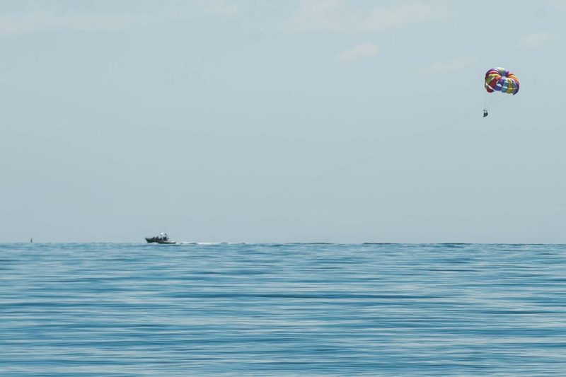 A parasailer skies above crystal waters at Harvest Caye in Belize.