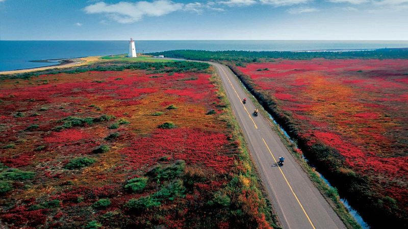 Visitors ride mopeds through a colorful fall landscape in Miscou Island, Canada, in the Gulf of St. Lawrence.