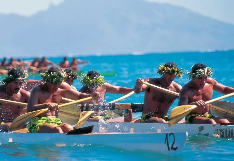 Tahitian outrigger races feature paddlers dressed in colorful pareos and traditional "heis" and leis for races and demonstrations.