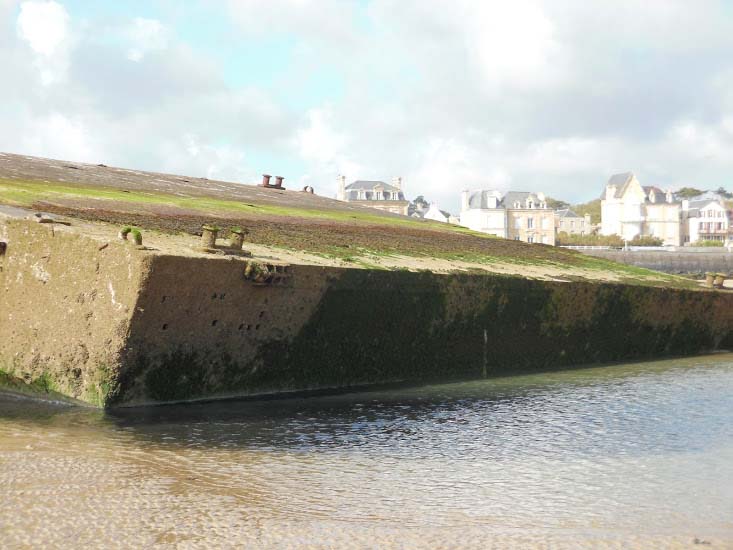 A cliffside wall holds back the sea at Normandy.