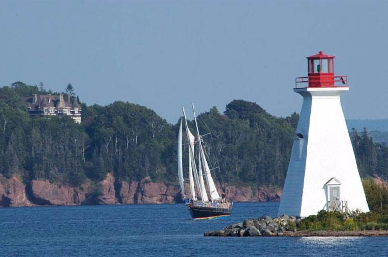 A sailing vessel passes a lighthouse in Baddeck, Nova Scotia.