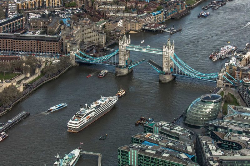 An aerial of Ponant's L'Austral sailing beneath Tower Bridge in London.