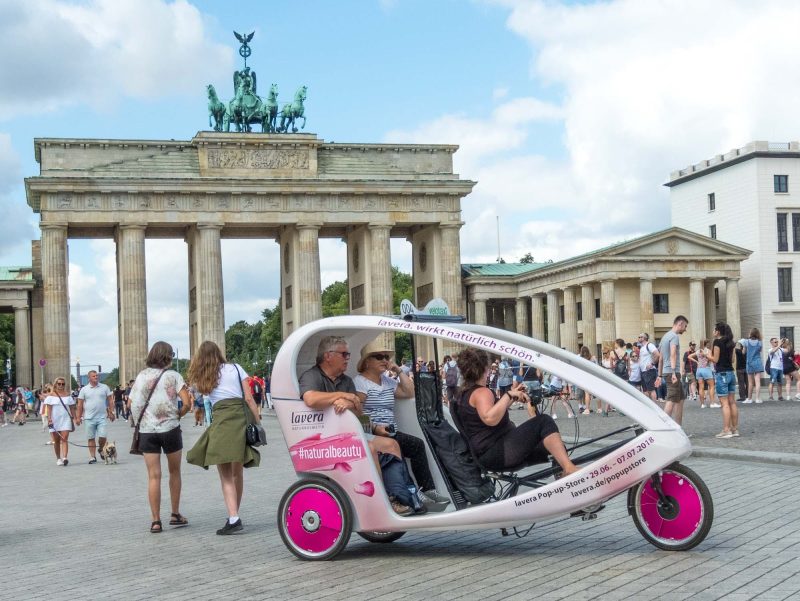 A pedal-powered pedicab picks up some tourists at Brandenburg Gate in Berlin.