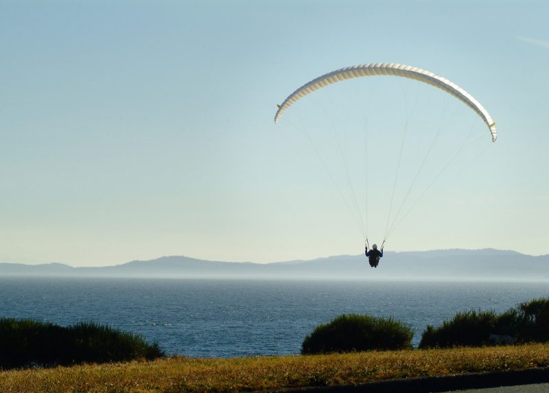 A paraglider soars across the bay near Victoria, British Columbia.