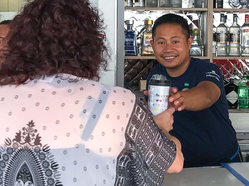 A wait staff member serves a passenger at Topsiders Grill on Norwegian Jade.