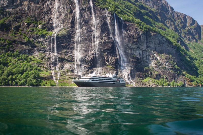 The Ponant ship L'Austral passes a waterfall in the Geiranger Fjord of Norway.