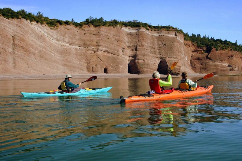 Kayakers explore the St. Martins Sea Caves, 25 miles east of St. John on the Bay of Fundy in Atlantic Canada.