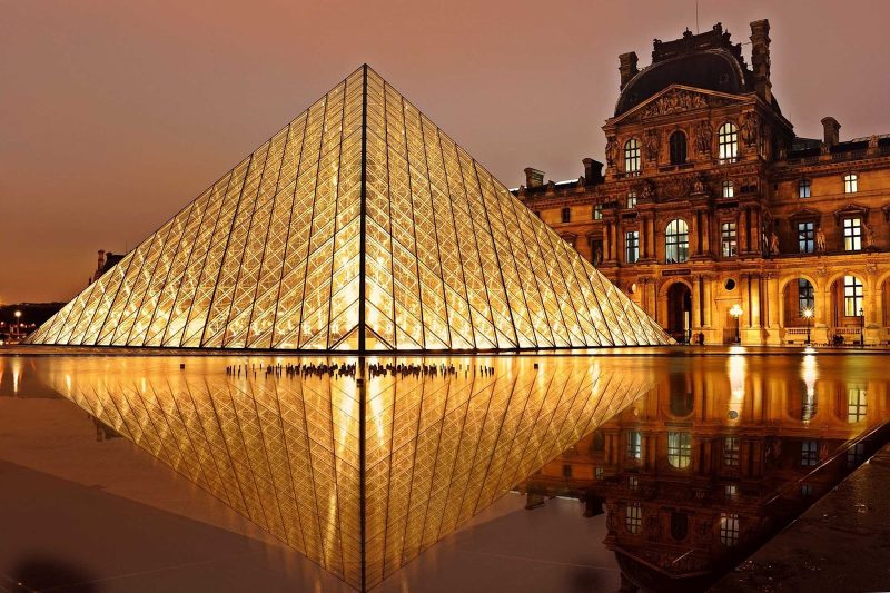 The Louvre Pyramid, in front of the Louvre Palace, illuminated at night in Paris.