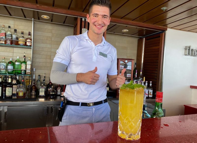 A mixologist shows off a Fog Cutter at the Sunset Bar on Celebrity Equinox.
