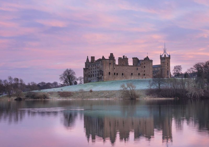 Linlithgow Palace and St. Michael's Parish Church at Linlithgow Loch, Scotland at twilight.