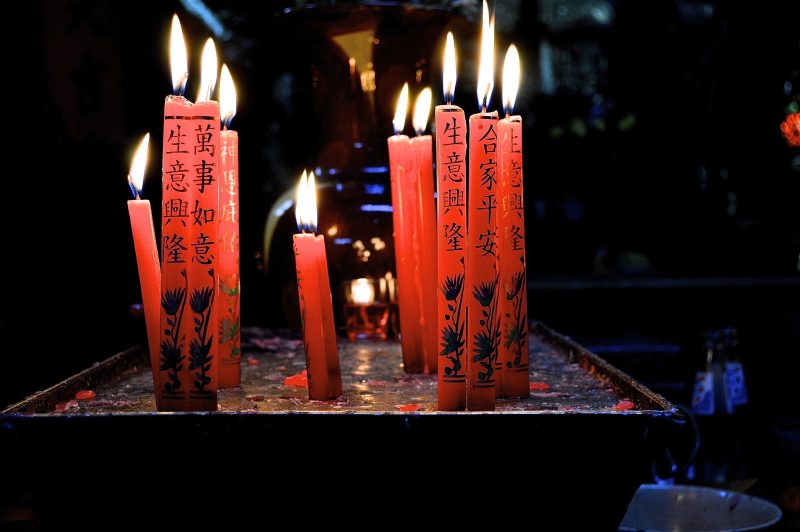 Red candles flicker in a beautiful Buddhist temple in Hanoi, Vietnam. 