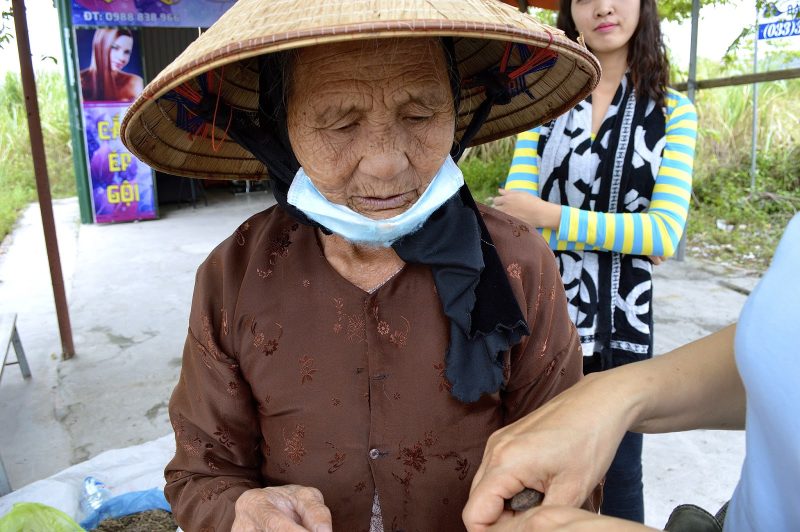 A woman merchant wears a typical hat to shield herself from the sun.