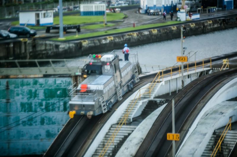 Electric locomotives, called "mules," guide a ship through a Panama Canal lock.